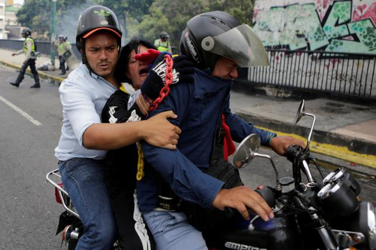 Một phụ nữ trúng hơi cay được chuyển khỏi hiện trường. Ảnh: REUTERS