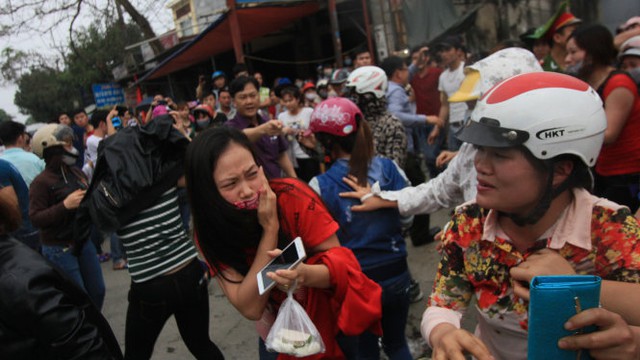  Một công nhân từ trong công ty chạy ra ngoài sợ hãi lấy tay che chắn đề phòng trứng thối, mắm tôi bay vào mặt - Ảnh: Tiến Thắng 