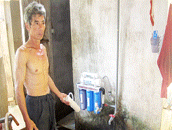 Nước bị ô nhiễm nên ông Lê Văn Cường phải mua máy về lọc nước để tắm