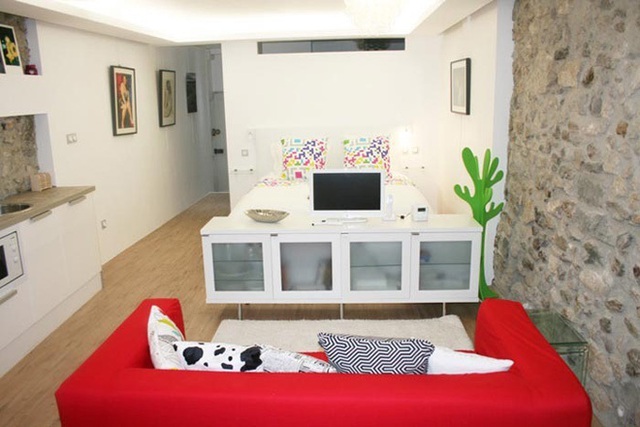 Còn ngôi nhà này được thiết kế với tông màu trắng của nội thất, màu nâu nhạt của tường đá giúp chiếc sofa đỏ nổi bật hơn.